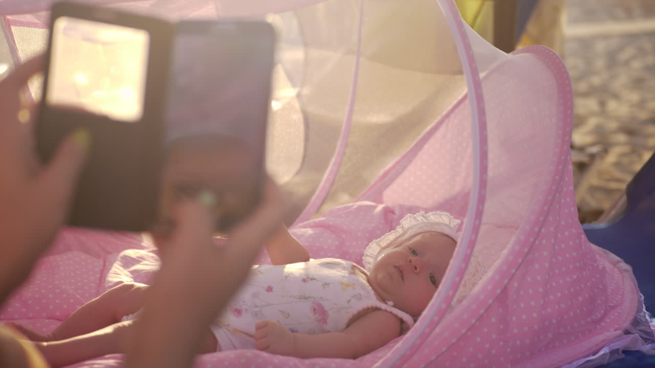 Mamma con cellulare che fotografa un neonato nella carrozzina all'aperto