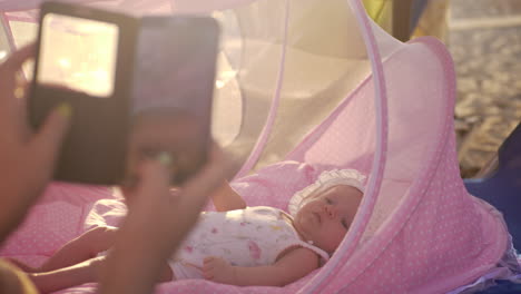 mom with mobile taking picture of baby in bassinet outdoor