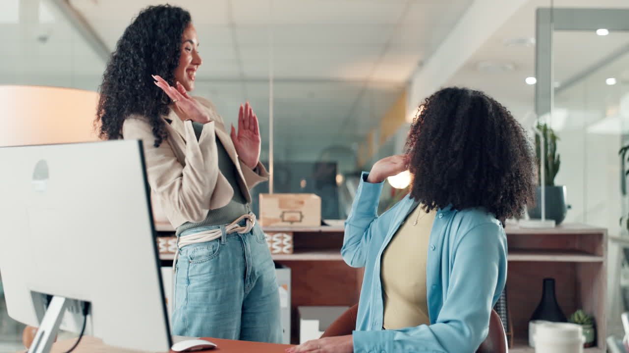 Two women celebrating success in a modern office