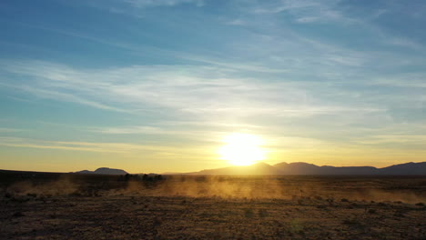 un penacho de polvo dejado en el sendero del desierto por una motocicleta que pasa o un vehículo todoterreno al atardecer - vista aérea