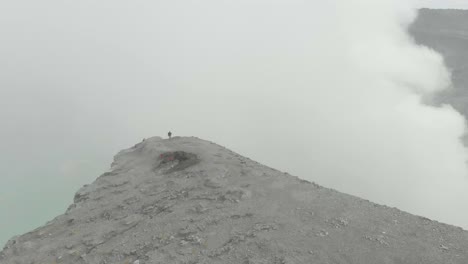 Traveler-stands-on-edge-of-volcano-crater-in-East-Java-with-thick-smoke