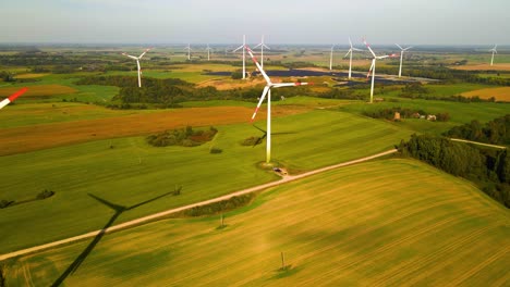 drone footage of wind turbines in a wind farm generating green electric energy on a wide green field on a sunny day, in taurage, lithuania