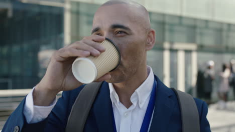 close up portrait of bald hispanic businessman looking facing camera drinking coffee corporate office