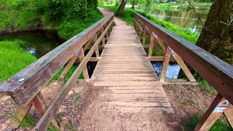 rustic wooden footbridge crossing small creek in lush green forest park