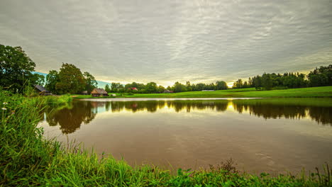 el tiempo del amanecer transcurre sobre una cabaña junto a un lago - el cielo se refleja en el agua