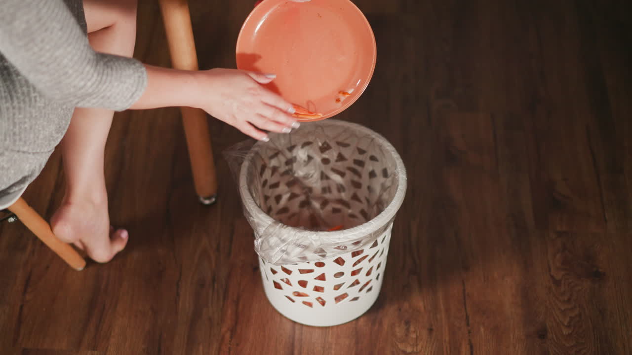 Woman discarding carrot scraps into a trash can