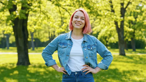young woman with pink hair smiling happily in a park