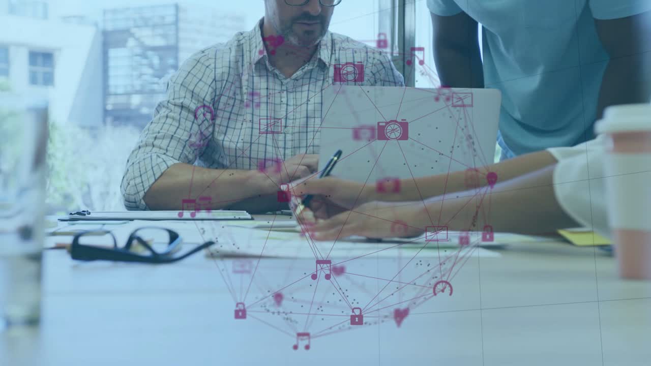 Gerente sentado señalando un portátil, iniciando el traspaso de un lápiz óptico, con colegas tomando notas para aplicaciones empresariales superpuestas.