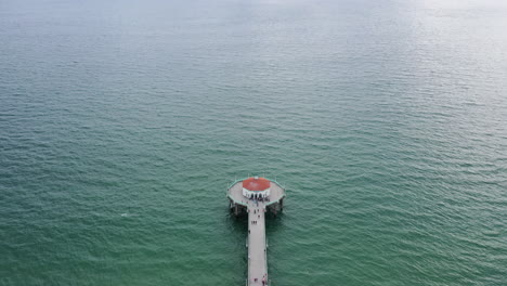 Holzsteg-Mit-Endlosem-Wasser-Und-Gebäude-Am-Ende,-Luftaufnahme