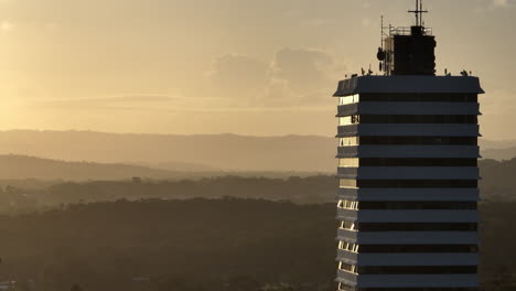 Teleschwenk-Drohnenparallaxen-Hochhaus-Mit-Blick-Auf-Die-Berge-Im-Hinterland-Bei-Sonnenuntergang,-Drohne-4k