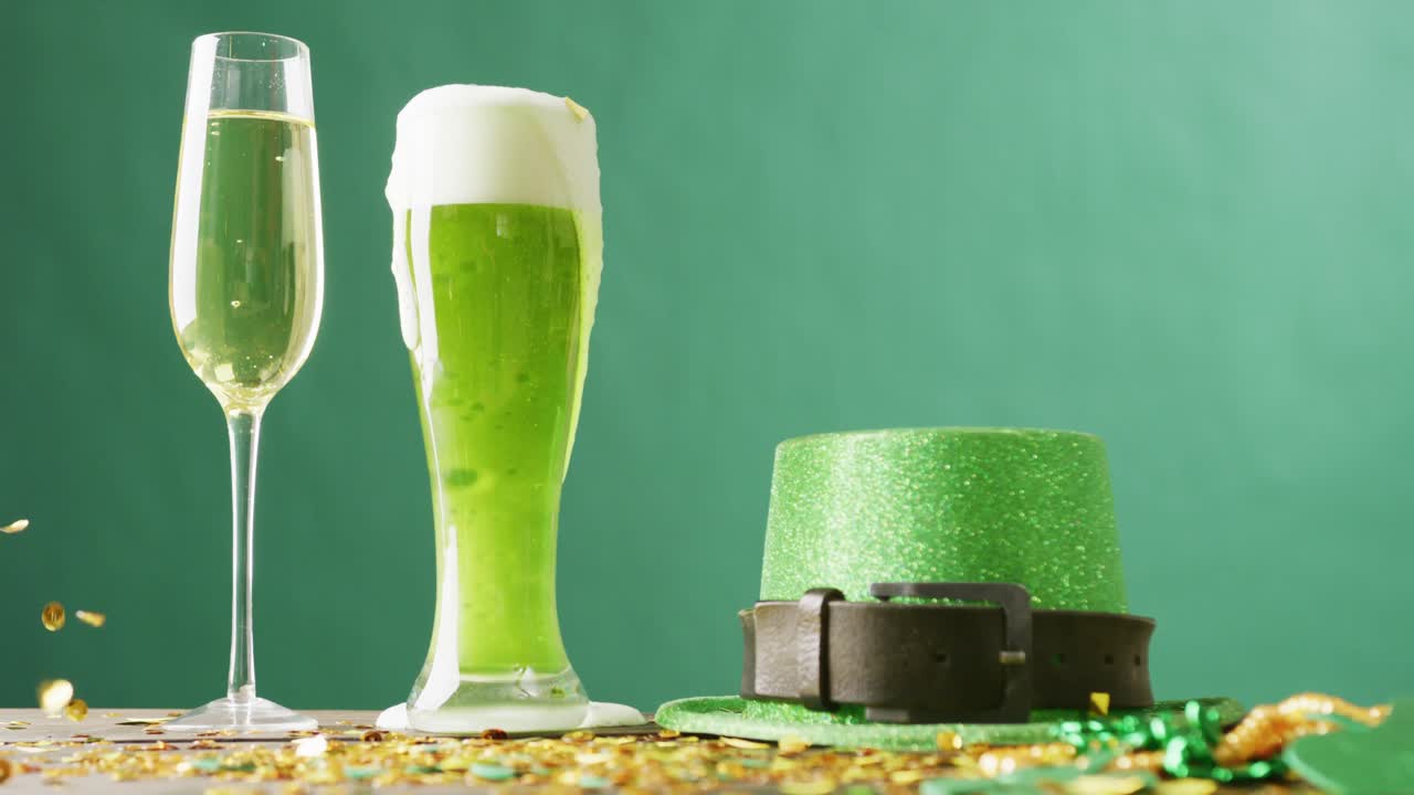 Video of st patrick's glass of champagne, beer, hat with copy space on green background