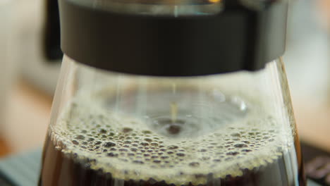 freshly brewed coffee dripping into transparent glass server in slow motion