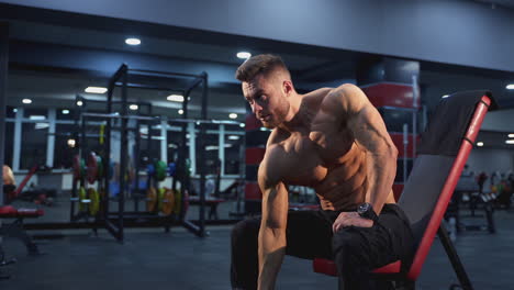 fitness guy pumping up arm muscles. bodybuilder training with a dumbbell in a modern fitness club. sportsman doing workout with heavy weight.