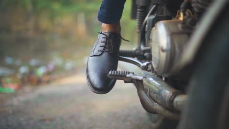 Closeup-shot-of-a-man-trying-to-kick-start-an-old-motorbike