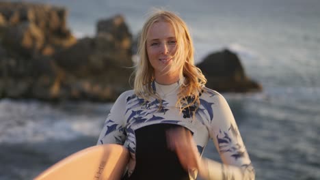 4k-Slow-motion-Close-up-portrait-of-young-smiling-surf-woman-with-blond-hair-blowing-in-the-wind-looking-at-the-sunset