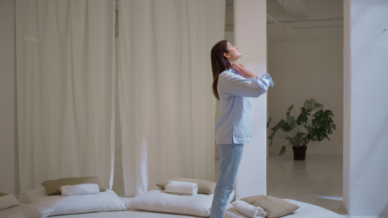 고요한 소녀가 몸을 펴고 집에서 아침에 손을 고 평화로운 모델이 숨을 쉬고 있습니다.