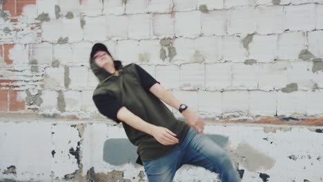 man hip hop dancing outside in city in front of brick wall