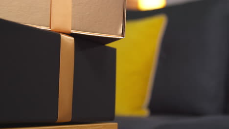 close up of person putting gift wrapped presents with bows on table in lounge at home