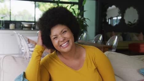video of happy plus size african american woman sitting on sofa