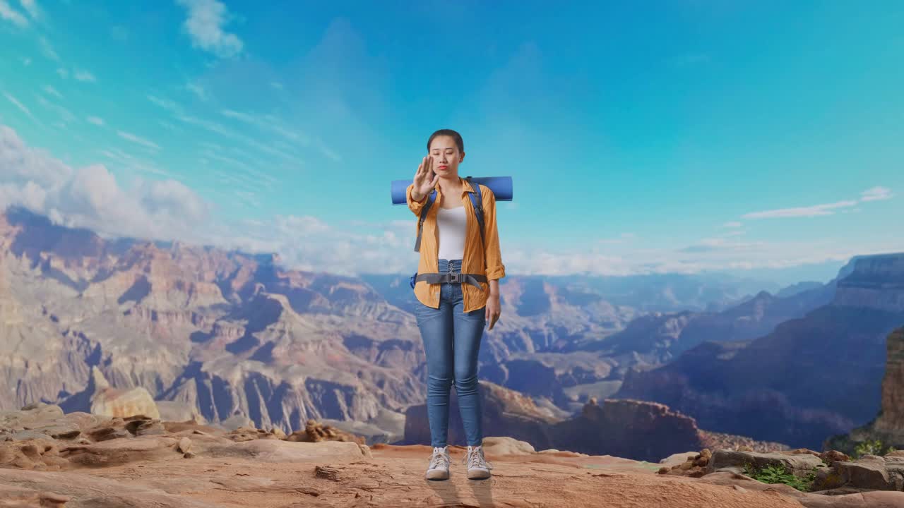 Full Body Of Asian Female Hiker With Mountaineering Backpack Looking At Camera And Making Stop Hand Sign While Traveling At The Top Of Mountain