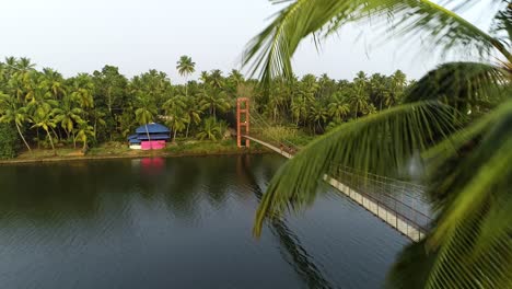 aerial flying backwards over river with footbridge in kochi, kerala