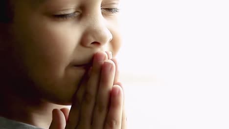 little-boy-praying-to-God-with-hands-together-on-white-background-with-people-stock-video-stock-footage