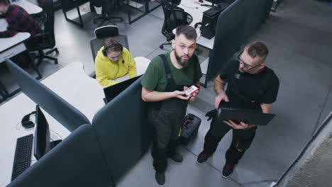 people working in a modern open-plan office, with one man taking a selfie