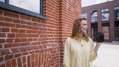 vrouwelijke fotograaf met camera voor de bakstenen muur