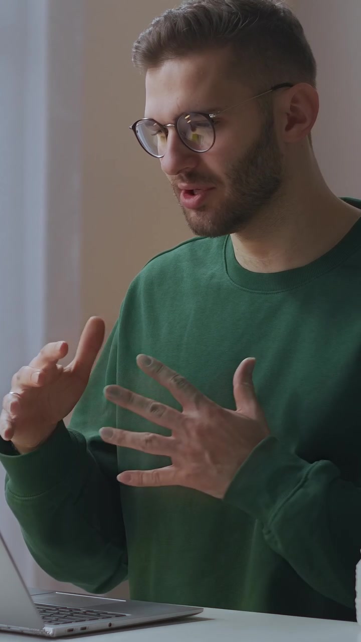Young Man Talking and Gesturing During Video Call on Laptop