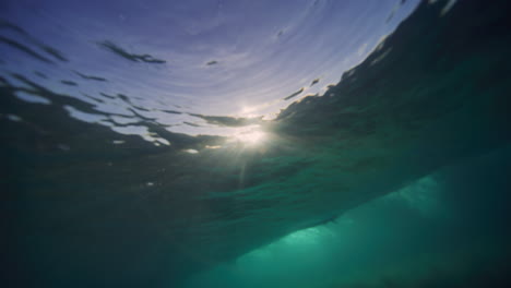 Low-underwater-view-of-light-sparkling-across-ocean-under-breaking-wave