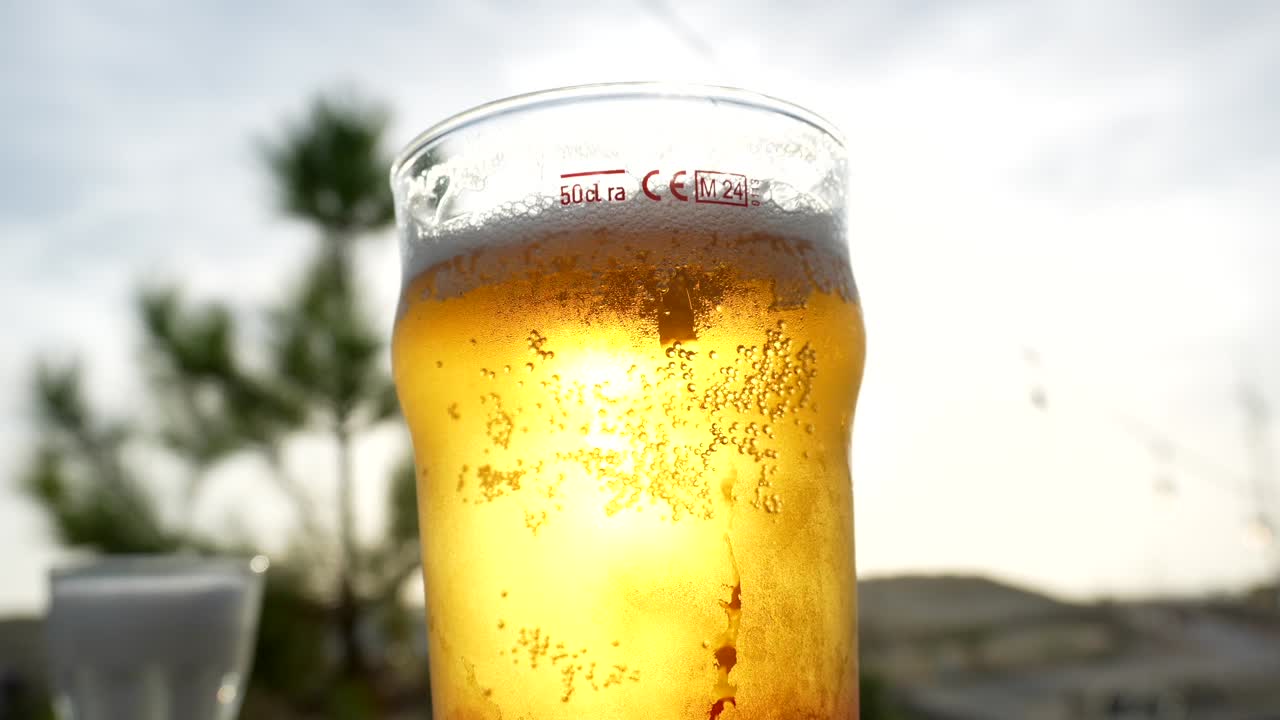 Primo piano di un rinfrescante boccale di birra con bollicine alla luce del sole