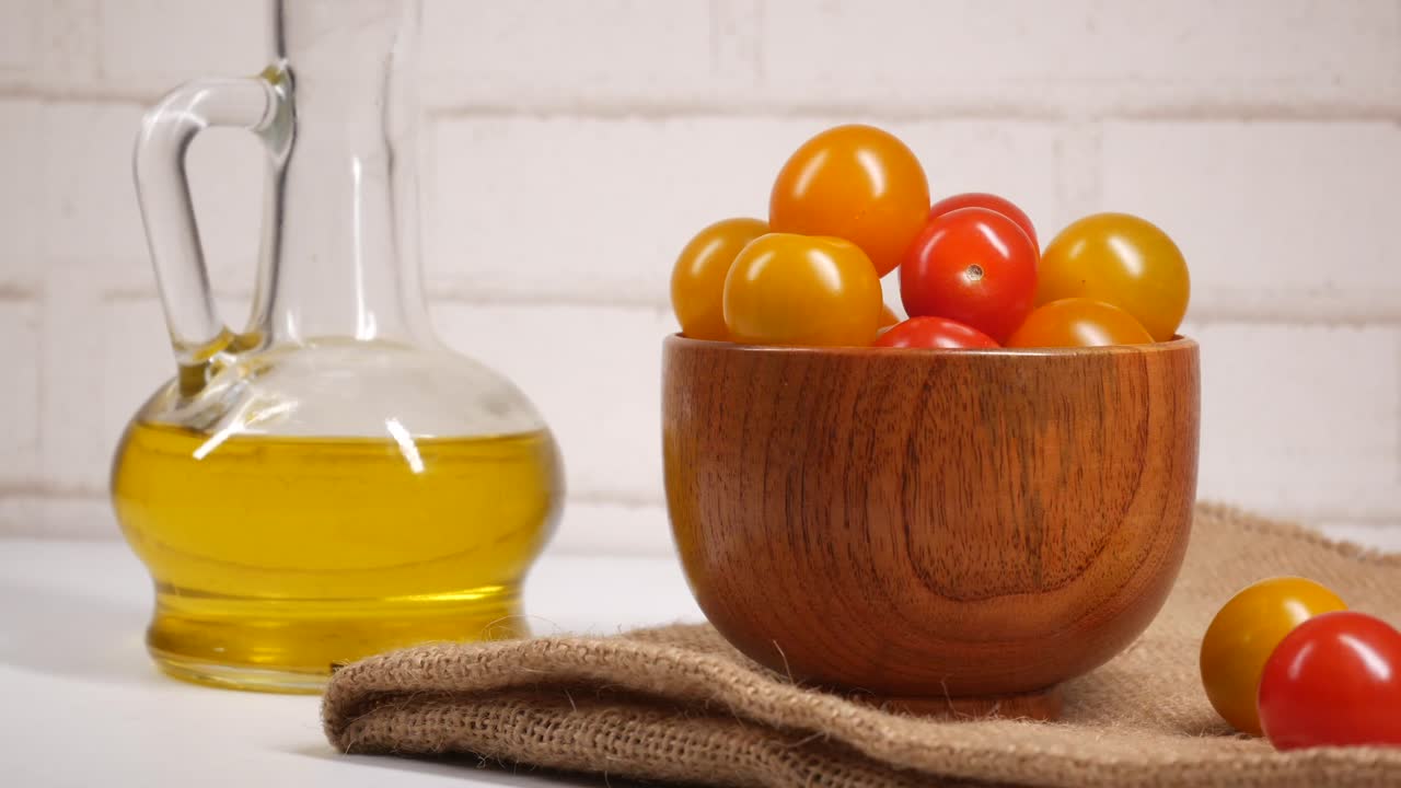 tomates cereza de colores en un cuenco de madera con aceite de oliva