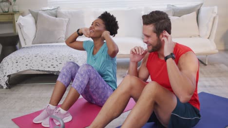 video of happy diverse couple training together at home, doing sit ups