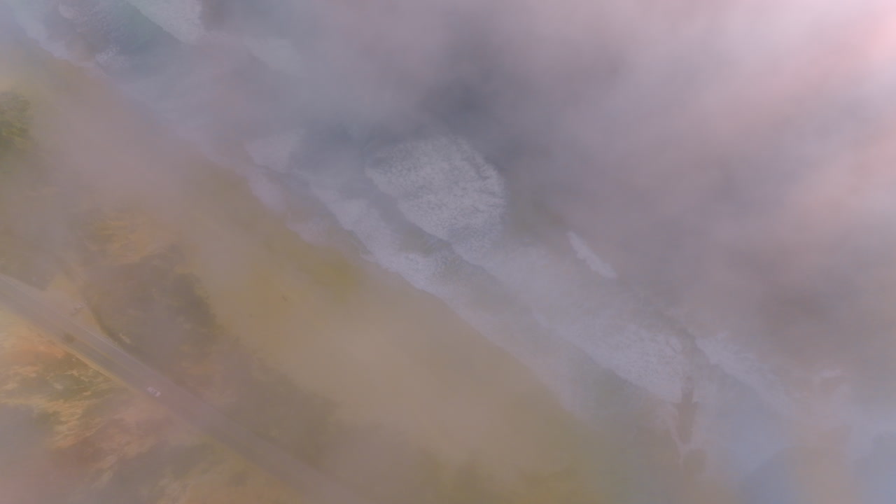 Scenery of a sandy beach with beautiful foamy waves approaching. Montara State Beach in a thick white fog from Pacific.