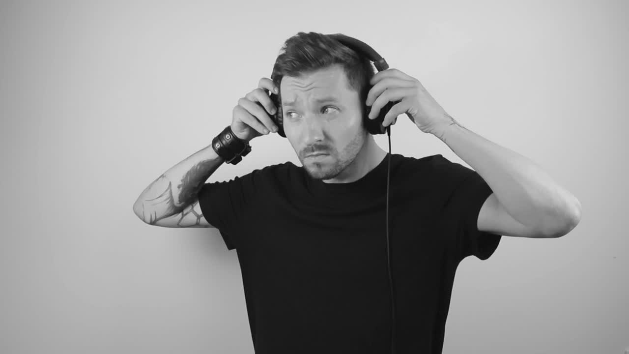 Sakte filmklipp av en mann som tar av seg store, svarte hodetelefoner etter å ha blitt distrahert av noe som skjer på siden