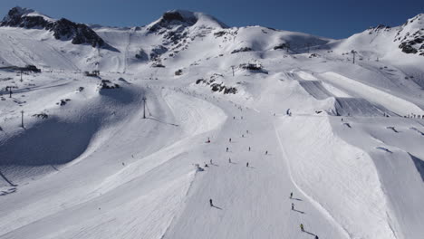 aerial view of many skiers skiing downhill snowy mountains in sun - austria,europe