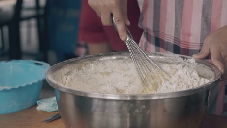 woman uses whisk for mixing dough in cafe kitchen closeup