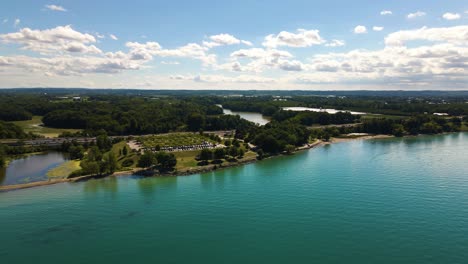 aerial view of the cars driving on a highway along beautiful green blue lake