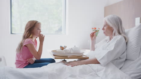 Granddaughter-Visiting-Grandmother-In-Hospital-Bed-For-Afternoon-Tea