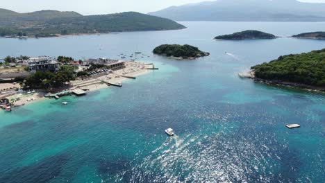 drone view in albania flying over white sand beaches, blue crystal clear water, green small islands, boats and hotels, sunny day in ksamil