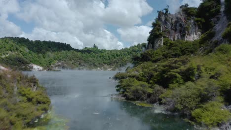 escurre agua desde un cráter termal hasta un lago volcánico humeante en nueva zelanda