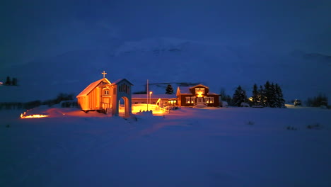 orange lit church next to a hotel in a thick pack of snow in iceland at night