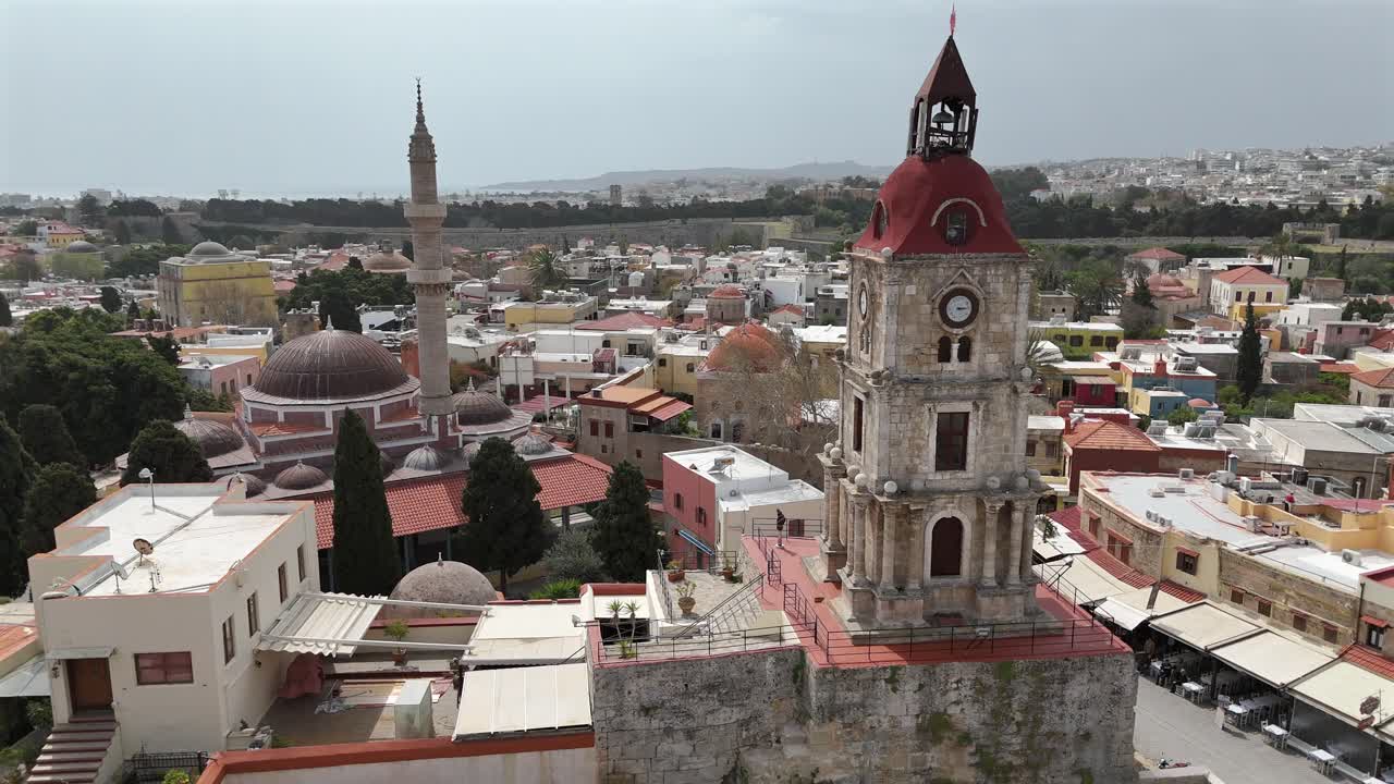 Aerial view circular pan left from Medieval Clock Tower and The Suleyman Mosque in the city of Rhodes in Rhodes island in Greece.Old town and city walls at the background on a sunny day.