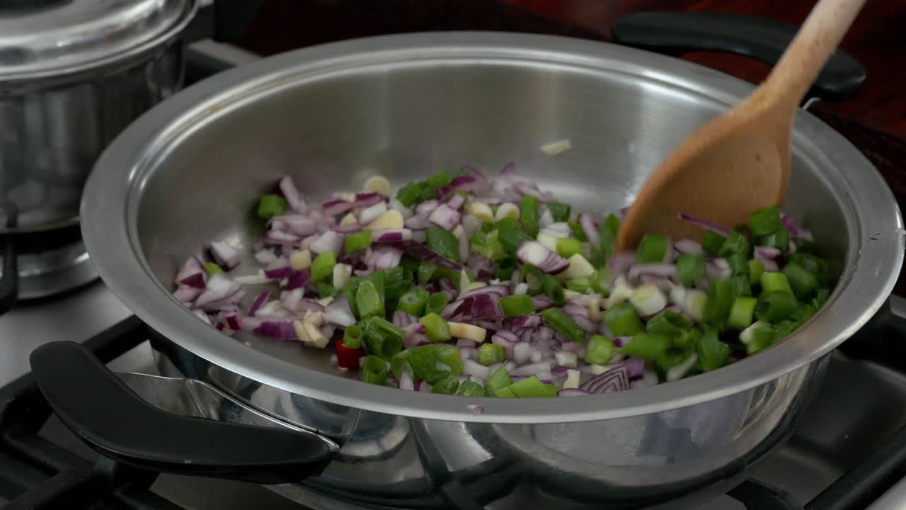 Chef stirring diced onions and celery in a pan with olive oil CLOSE UP