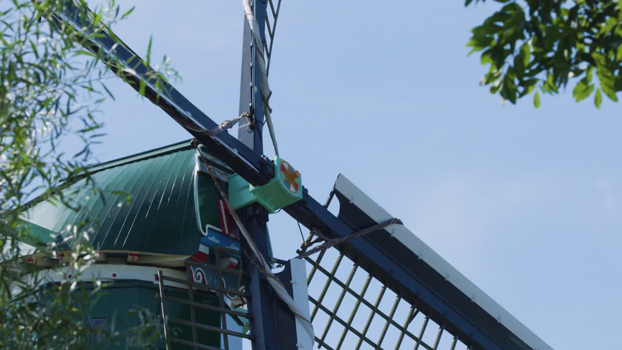 Close-up of windmill blades turning, green dome visible, natural daylight, gentle camera movement
