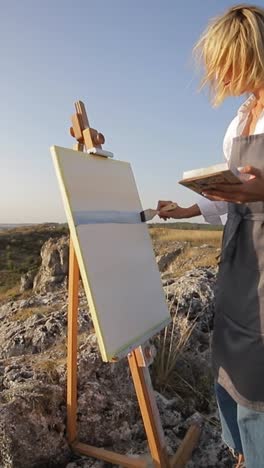 woman painting a scenic landscape outdoors on an easel