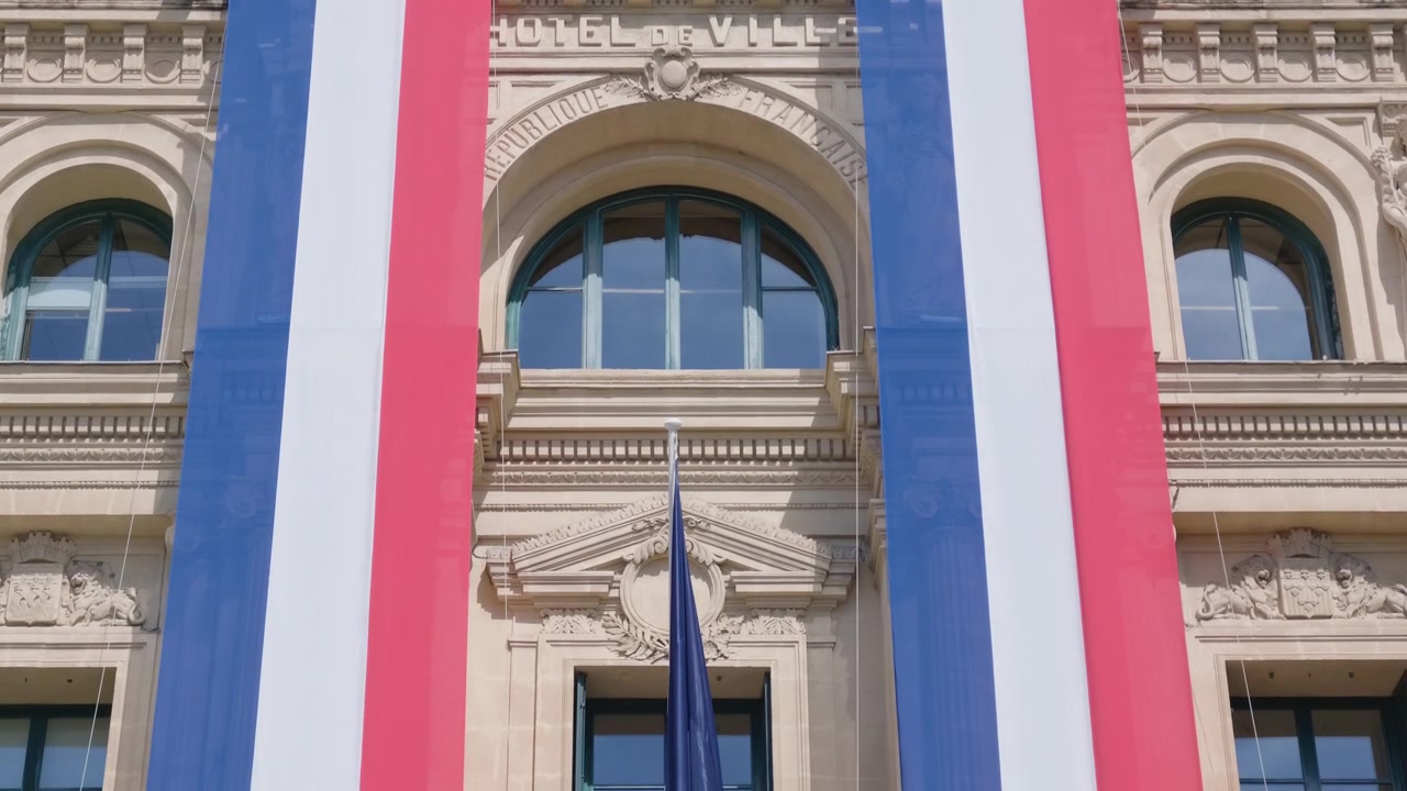 Vista ravvicinata della facciata dell'Hotel de Ville con finestre ad arco e un grande striscione con la bandiera francese, Cannes, Francia