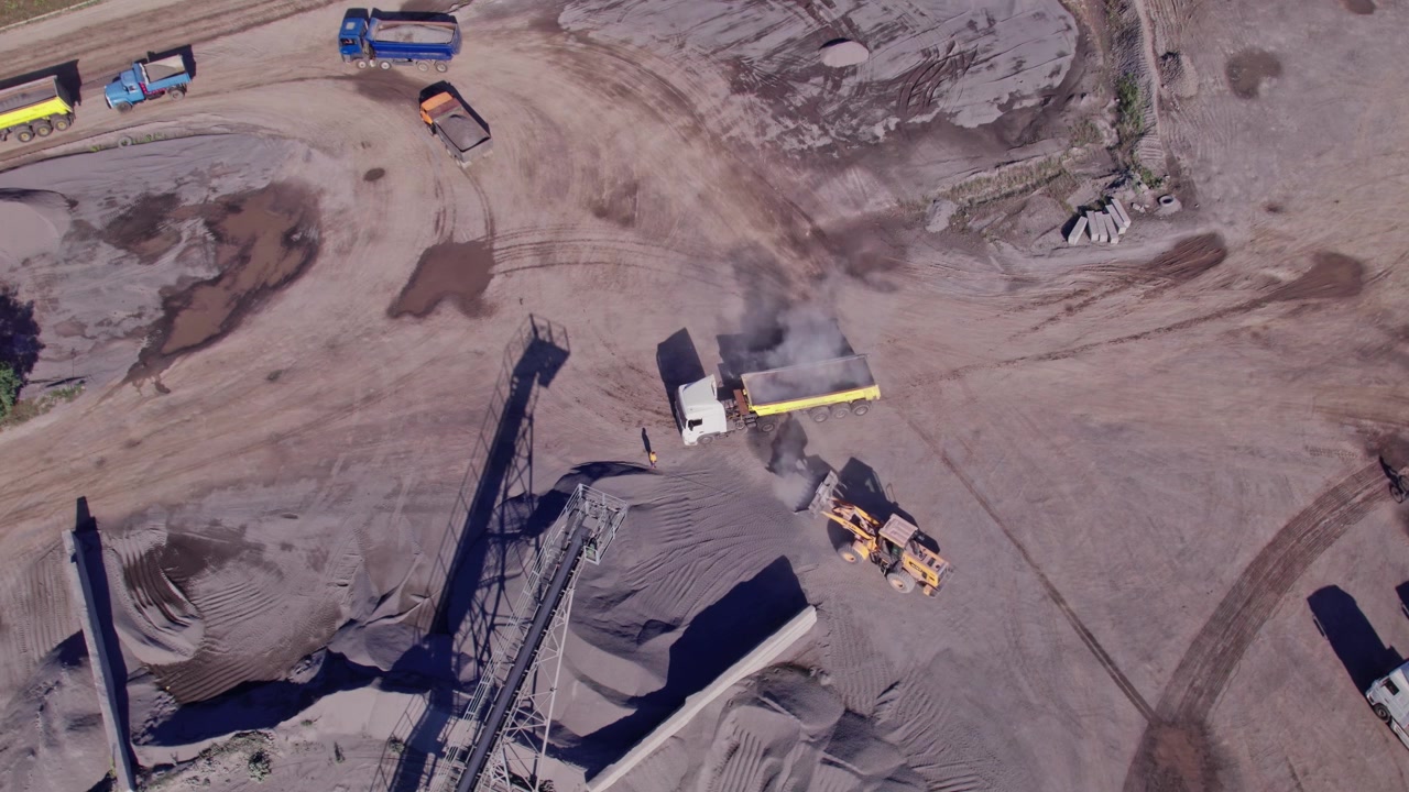 Trucks moving sand and gravel in a busy quarry area