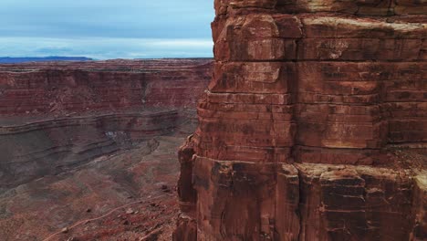 Aerial-wide-giant-rock-face-tracks-to-reveal-Utah-red-rock-canyon