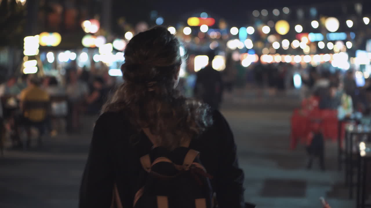 mujer caminando por un bullicioso mercado nocturno